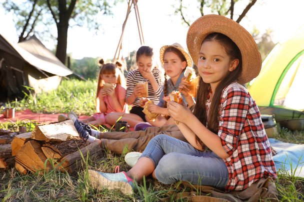 Little girl eating sandwich outdoors. Summer camp - Foto, Imagen