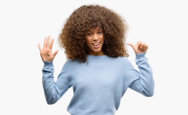 Donna afroamericana che indossa un maglione mostrando e indicando con le dita il numero sei mentre sorride fiducioso e felice
. - Foto, immagini