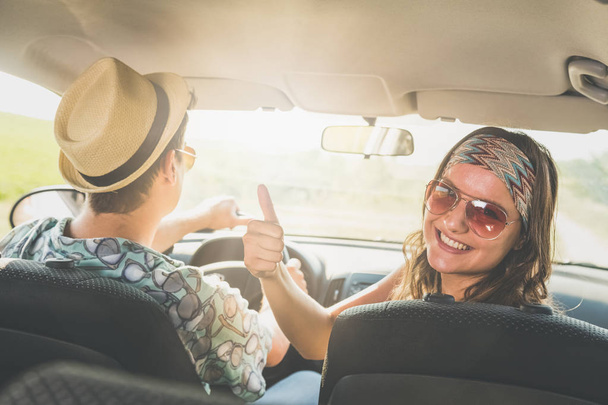 Portrait of young fashionable female with her boyfriend showing thumbs up in car interior. - Foto, Imagem