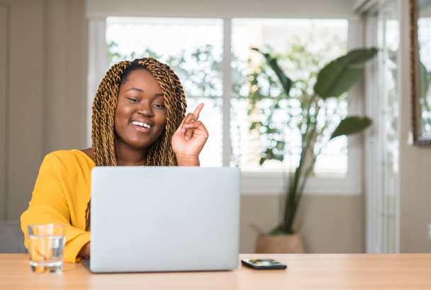 幸せそうな顔でアイデアや質問ポインティング指で驚きのラップトップでアフリカ系アメリカ人の女性がナンバーワンします。 - 写真・画像