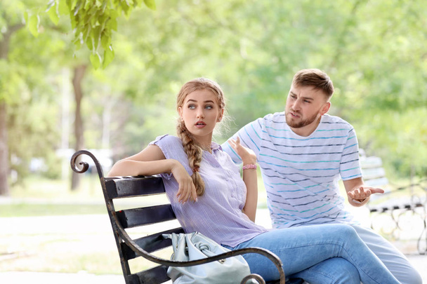 Young couple arguing while sitting on bench in park. Problems in relationship - Fotó, kép