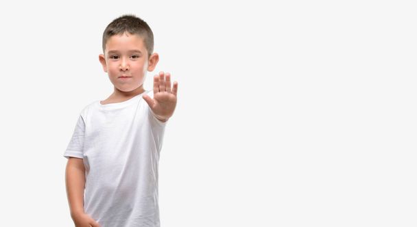 Темноволоса маленька дитина з відкритою рукою робить знак зупинки з серйозним і впевненим виразом, жест захисту
 - Фото, зображення