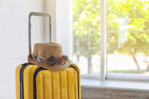 Világos sárga bőrönd, kalap és napszemüveg beltéri - Fotó, kép