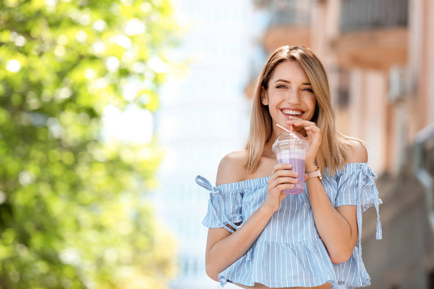 Young woman with plastic cup of healthy smoothie outdoors - 写真・画像