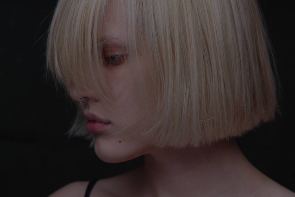 portrait of blonde woman with bob hairstyle on dark background  - Fotó, kép