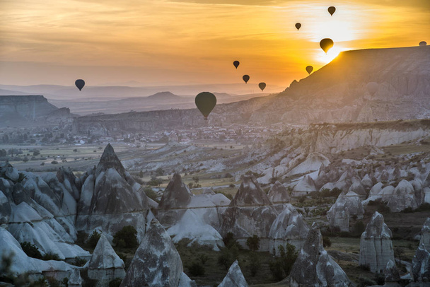 Hete-lucht ballonnen tegen zonsopgang scène. Cappadocië. Beroemde rotsen van Cappadocië in voorgrond. - Foto, afbeelding