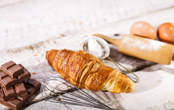 Baked croissants and ingredients for the preparation of bakery products. Rustic style. White wooden background. - Photo, image