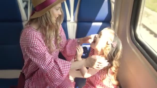 Krásná maminka a roztomilý dcera pacičky sedí u okna v rychlosti vlaku - Záběry, video