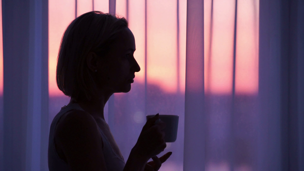 Vrouw koffie drinken bij zonsopgang. silhouet van een vrouw - Video
