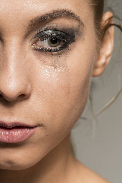 Triest huilend meisje op zoek naar beneden met vlekkerig make-up close-up shot - Foto, afbeelding
