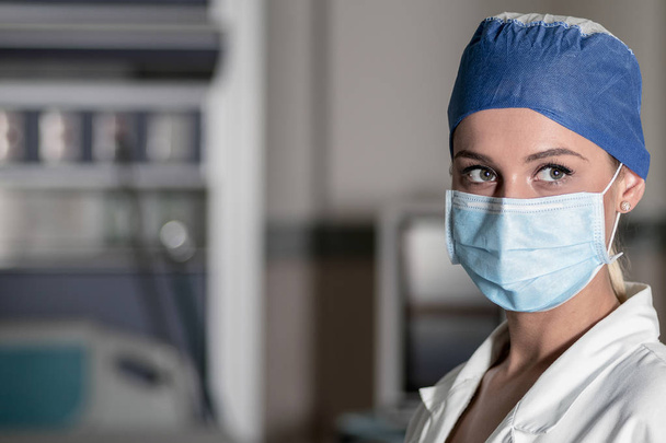Genç sarışın hemşire acil odasında bir ameliyat maskesi ve cerrahi kap - Fotoğraf, Görsel