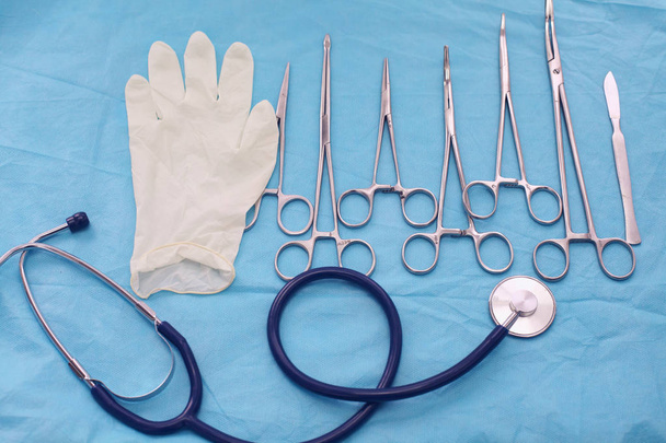 Ameliyat için masaya yerleştirilmiş neşter, pens ve cımbız gibi cerrahi aletler ve aletler. - Fotoğraf, Görsel