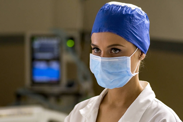 Genç sarışın hemşire acil odasında bir ameliyat maskesi ve cerrahi kap - Fotoğraf, Görsel