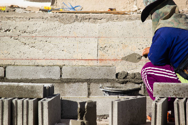 Maurer oder Ziegelbauer bauen Zementmauern auf Baustellen. Arbeiter bauen Gebäude oder Gebäude für Wohnungen. - Foto, Bild