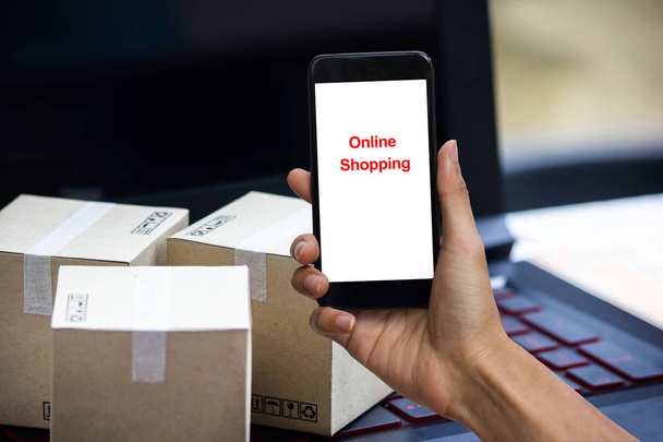 Online winkelen concept e-commerce levering service kopen. vierkante dozen winkelen op laptop toetsenbord, waaruit de order van de klant via internet op smartphone. - Foto, afbeelding