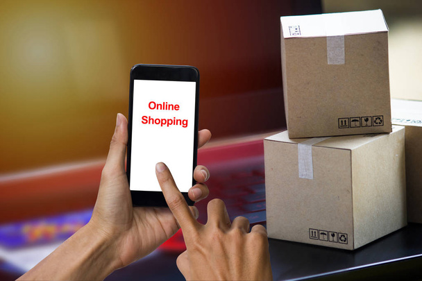 Концепция интернет-покупок e-commerce - услуга покупки с доставкой. квадратные коробки покупки на клавиатуре ноутбука, показывая заказ клиента через интернет на смартфоне
. - Фото, изображение