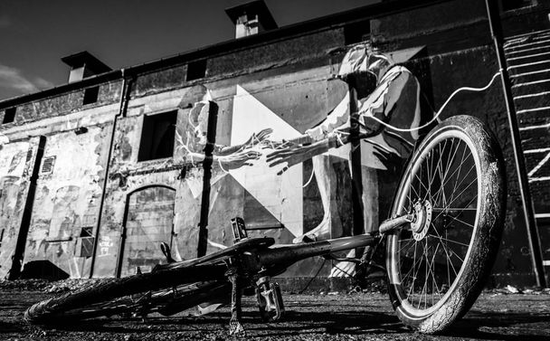 A bike on the ground, old buildings with graffiti in the back - black and white - Photo, Image