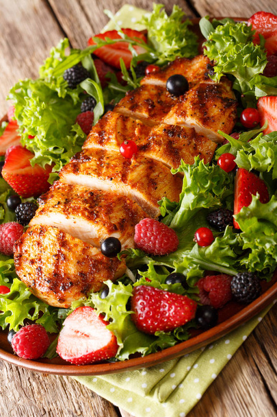 Organic salad of grilled chicken breast with fresh berries, lettuce and arugula closeup on plate on table. vertica - Photo, Image