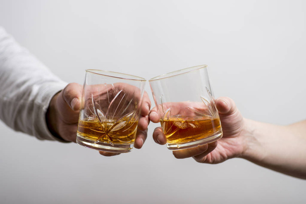 zwei Männer klirren Gläser mit alkoholischen Getränken zusammen, während - Foto, Bild