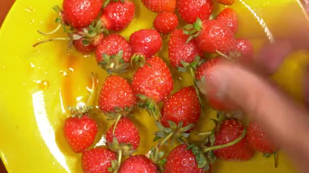 Hands take a red ripe strawberry from a yellow dish, 4k, time lapse - Video, Çekim