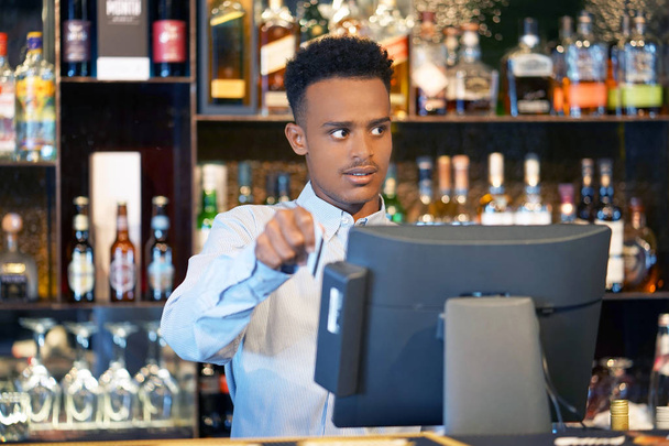 Homem de registro de empregado de bar de uma nova ordem por uma caixa registradora. O barman paga a encomenda com um cartão de crédito. Conceito de serviço. Close-up. - Foto, Imagem