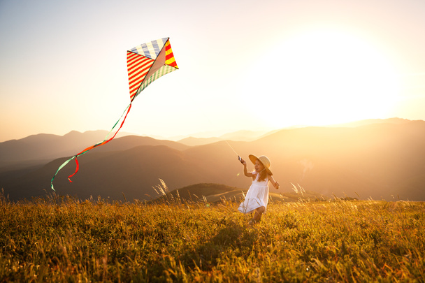 happy child girl running with a kite at sunset outdoor - Photo, Image