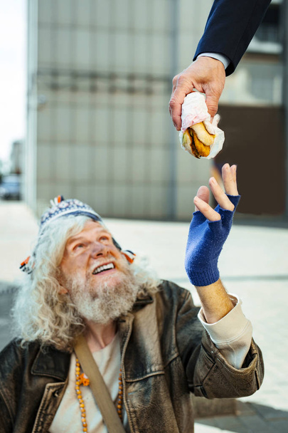 Homeless man taking burger from kind stranger - Фото, изображение