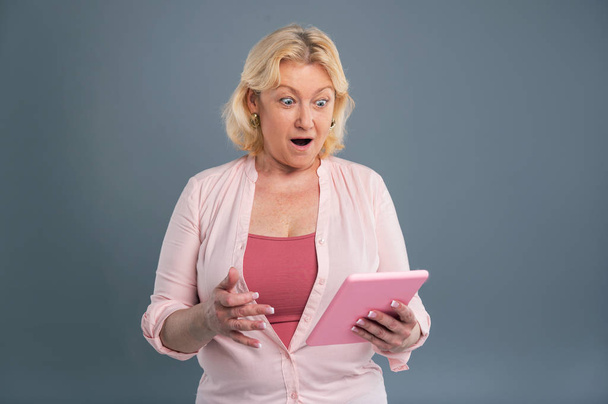 Cheerful middle-aged woman looking stunned after reading message - Foto, Bild