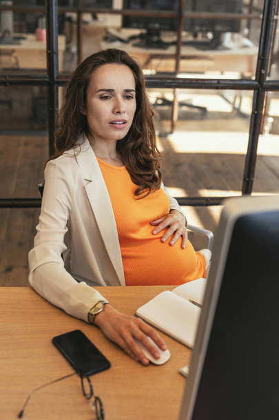 Concerned pregnant CEO preparing report - Foto, immagini