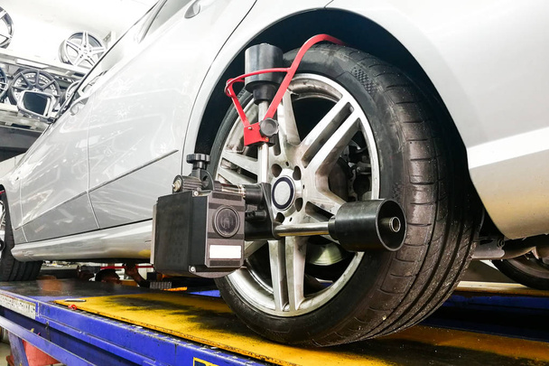 Carro sofre alinhamento de roda na garagem com equipamentos de alinhamento de precisão
 - Foto, Imagem