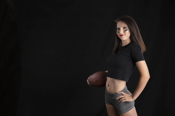 Una modella bruna che tiene un calcio in un ambiente da studio
 - Foto, immagini
