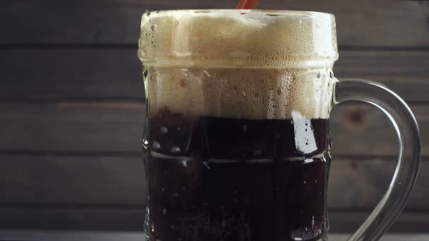 Verter cerveza fría y oscura en la taza de cerveza. Sobre fondo de madera oscura. Movimiento lento
 - Metraje, vídeo