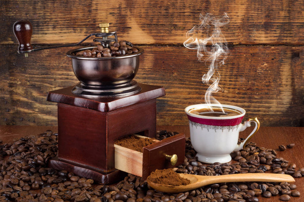 Moulin à café Burr broyeur et tasse de café avec fumée et cuillère en bois sur fond rétro. Concept de boisson rétro et vintage
 - Photo, image