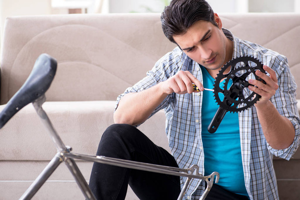 Young man repairing bicycle at home - Foto, afbeelding