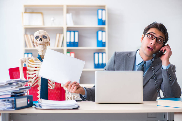 Empresário trabalhando com esqueleto no escritório - Foto, Imagem