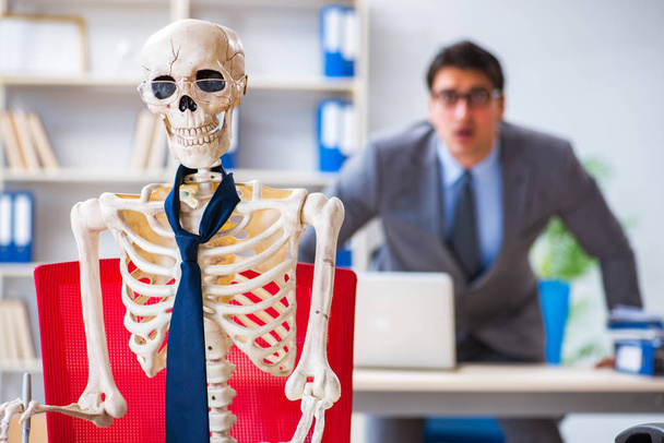 Uomo d'affari che lavora con scheletro in ufficio - Foto, immagini
