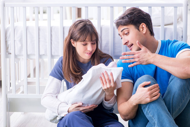 Νέοι γονείς με το νεογέννητο μωρό τους να κάθεται στο χαλί  - Φωτογραφία, εικόνα