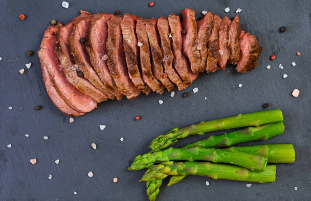 Grilled beef steak and asparagus on wooden background - Photo, image