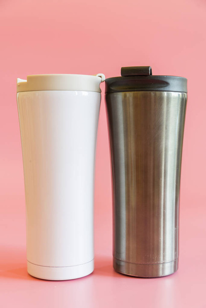 two insulated cups on a pink background. Thermo cup, thermo glasses. The concept of a hike and free life. - Foto, immagini