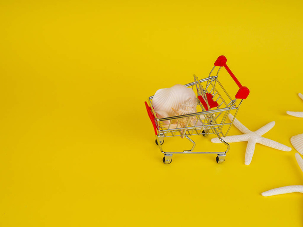 supermarket trolley on yellow background, shells inside, release, Concept of shopping. Copy space for advertisement - Foto, Bild
