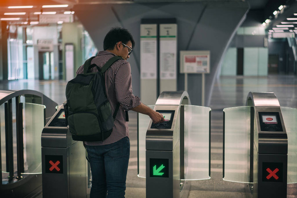 Νεαρά ασιατικές ταξιδιώτης χρησιμοποιώντας έξυπνη κάρτα pass την πόρτα στο τρένο μάζα ταχείας διέλευσης (Mrt) στην Κουάλα Λουμπούρ. MRT σύστημα που αποτελούν το κύριο συστατικό του σιδηροδρομικού συστήματος στην Κουάλα Λουμπούρ, Μαλαισία. - Φωτογραφία, εικόνα