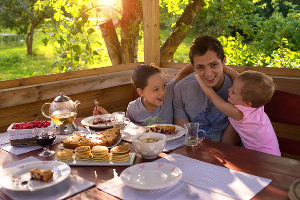 Desayuno familiar en una casa de campo. niños felizmente acurrucados con papá
 - Foto, Imagen