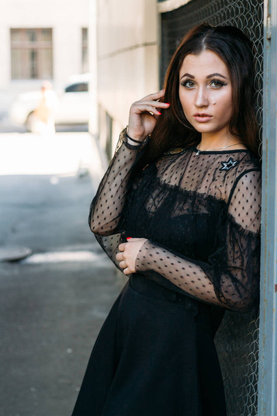 Emotional portrait of Fashion stylish portrait of pretty young woman. city portrait. sad girl. brunette in a black dress with stars and planets on a dress. expectation. dreams - Фото, изображение
