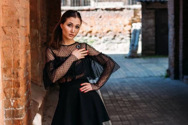 the girl is posing. Emotional portrait of Fashion stylish portrait of pretty young woman. city portrait. sad girl. brunette in a black dress with stars and planets on a dress. expectation. dreams - Fotografie, Obrázek