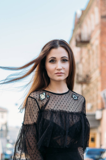 Emotional portrait of Fashion stylish portrait of pretty young woman. city portrait. sad girl. brunette in a black dress with stars and planets on a dress. expectation. dreams. girl - night in the middle of the day - Foto, imagen