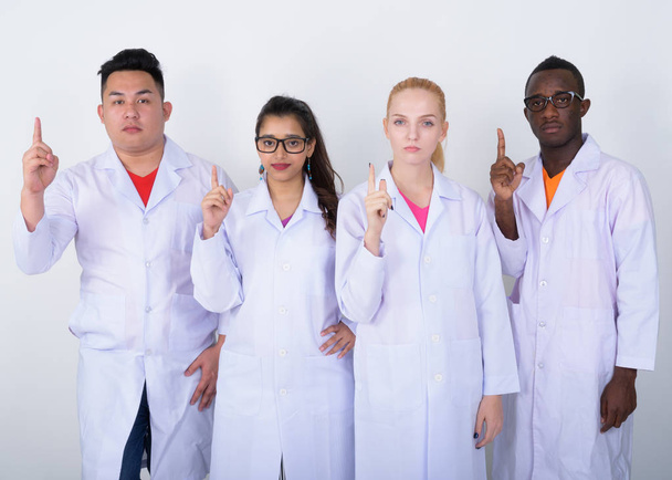Студійний знімок різноманітної групи етнічних лікарів, що вказують на
 - Фото, зображення