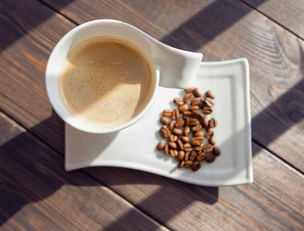 tazza bianca di caffè con grani su uno sfondo di legno
 - Foto, immagini