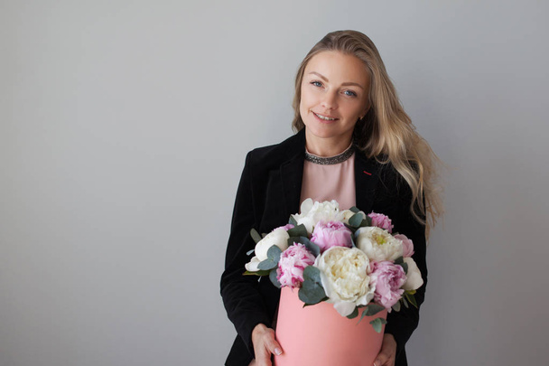 Charming blonde woman with flowers in a hat box. Bouquet of peonies. - Fotografie, Obrázek