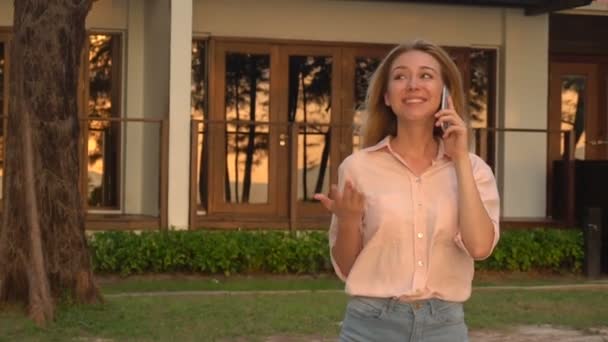 Chica economista de cámara lenta hablando en smartphone caminando cerca del hotel
 - Imágenes, Vídeo
