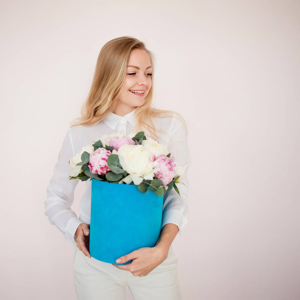 Stylish flower delivery, gift. Woman with flowers in a hat box. Bouquet of peonies. - Valokuva, kuva